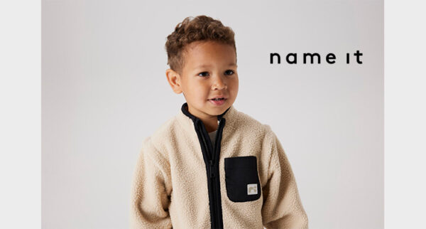 Kind mit cremefarbenem Fell Sweater und schwarzem Reißverschluss und schwarzer Brusttasche von nameit