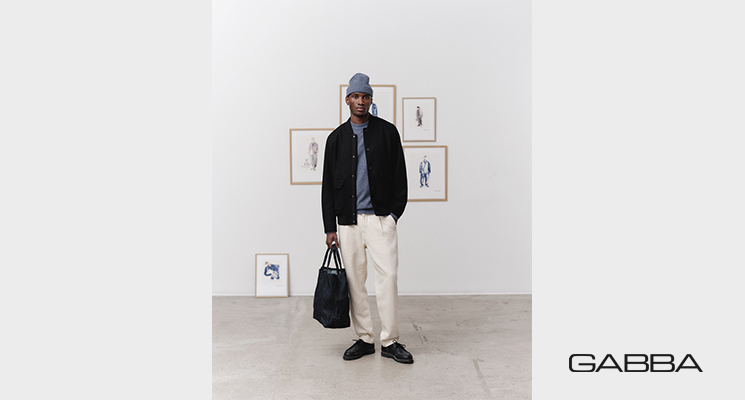 Mann mit weißer Hose, blauem Pullover und schwarzen Hemd von Gabba