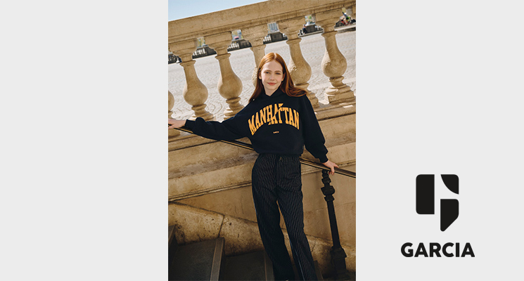 Mädchen gekleidet in schwarzem Pullover mit gelbem Aufdruck von Garcia