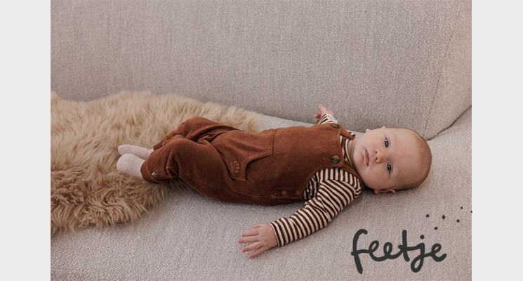 Baby mit braunem Strampler und gestreiftem Shirt von feetje