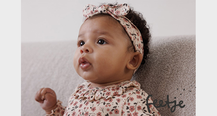 Kind mit geblümtem Haarband und Oberteil von feetje