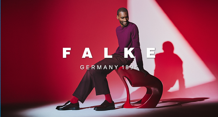 Gekleideter Mann mit roten Falke Socken, der auf rotem Stuhl sitzt