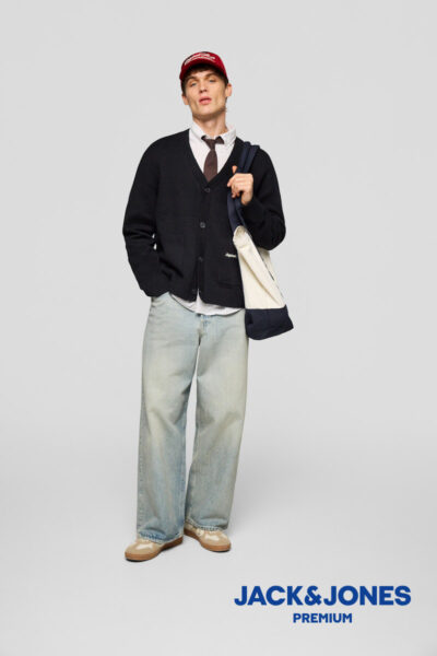 Mann mit blauer Jeans, schwarzer Jacke mit Knöpfen, darunter weißes Hemd mit Krawatte und Cap von Jack & Jones