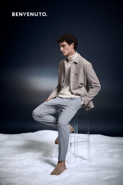 Sitzender Mann mit grauer Hose, naturfarbenem Rollkragenpullover und beiger Jacke von Benvenuto