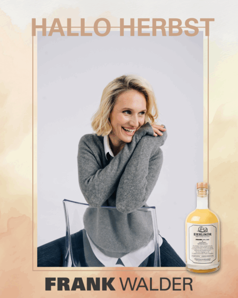 Dame auf Stuhl sitzend mit grauem Pullover, darunter weißer Bluse und schwarzer Hose.