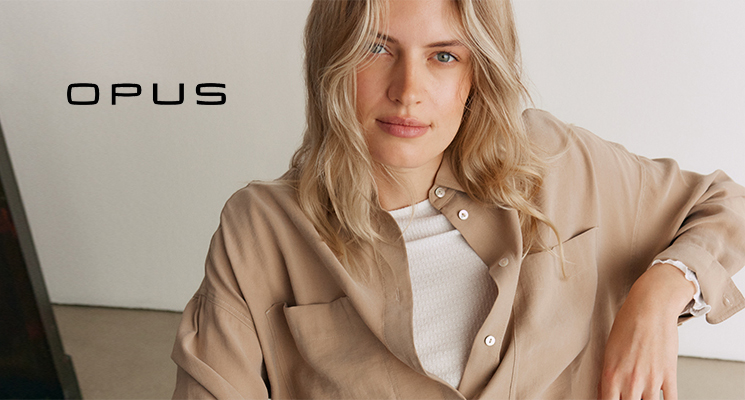 Frau mit beiger Bluse, beigem Shirt und blauer Jeans sitzend auf Stuhl von Opus