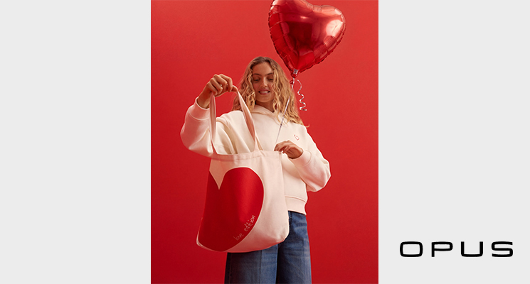 Frau stehend mit Herztasche, weißem Hoodie mit Herz und blauer Jeans zum Valentinstag von Opus