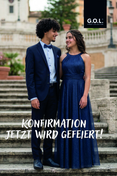 Junges Paar im Anzug und festlichem Kleid der Marke GOL stehend auf einer Treppe