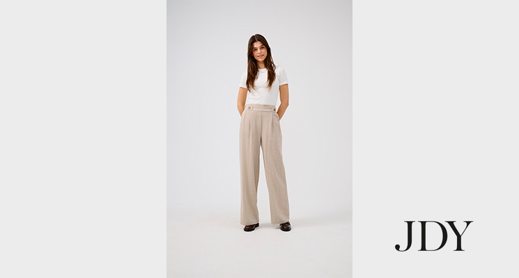 Frau stehend mit weißem T-Shirt und beiger Stoffhose von JDY