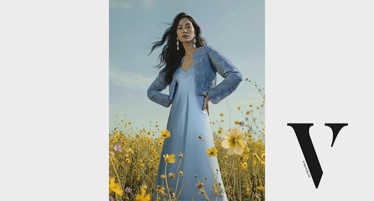 Frau auf Wiese stehend in hellblauem festlichen Kleid und blauem Jäckchen