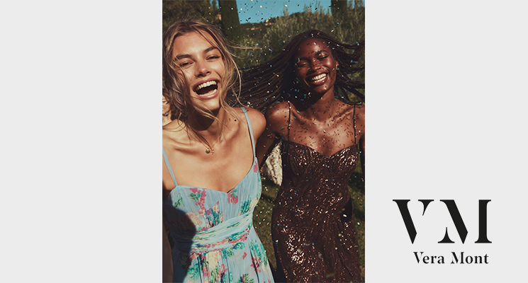 2 Frauen lachend in festlichen Kleidern in blau mit Blumenmotiv und braun mit Glitzerpailetten