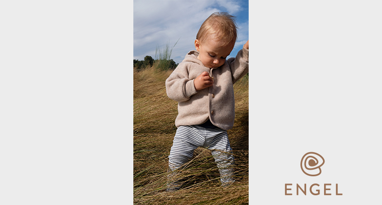 Kind in Kapuzenjacke und gestreifter Hose auf Wiese von Engel