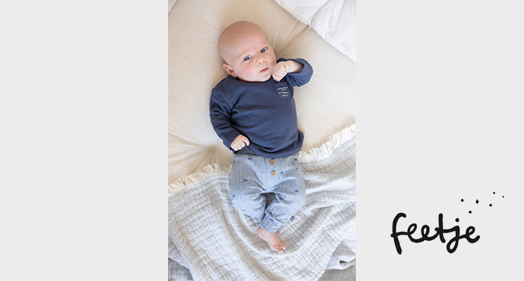 Baby liegend mit dunkelblauem Langarmshirt und hellblauer Hose von Feetje