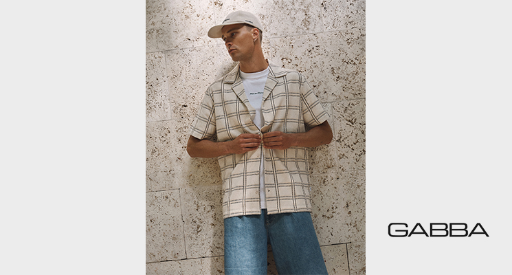 Mann mit beige kariertem Hemd, weißem T-Shirt darunter und blauer Jeans von Gabba