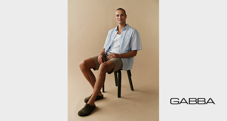 Sitzender Mann in hellblauem Hemd, weißem T-Shirt und beiger kurzer Hose von Gabba