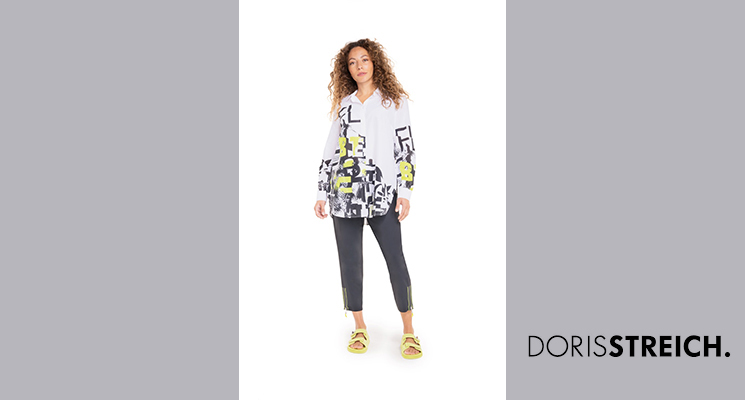 Frau mit weißer Bluse mit schwarzem und neongrünem Druck und blauer Hose von Doris Streich