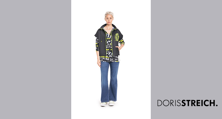 Frau mit schwarz/weiß/neongrünem Printlangarmshirt und schwarzer Weste sowie blauer Jeans von Doris Streich