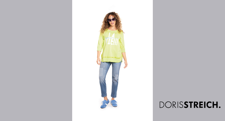 Frau mit neongrünem 3/4 Arm Shirt mit weißem Druck und blauer Jeans von Doris Streich