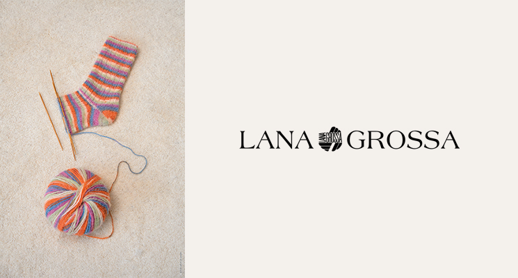 1 bunter Wolleknäuel mit Stricknadeln und angefangenem gestrickten Socken