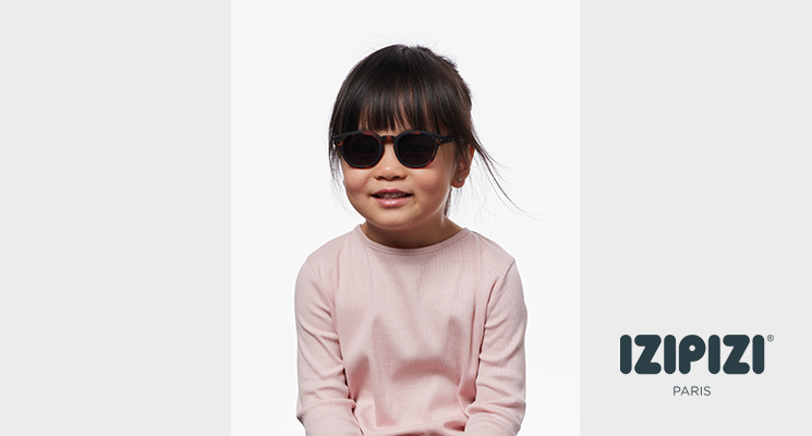Kind mit dunkelbrauner Sonnenbrille von Izipizi