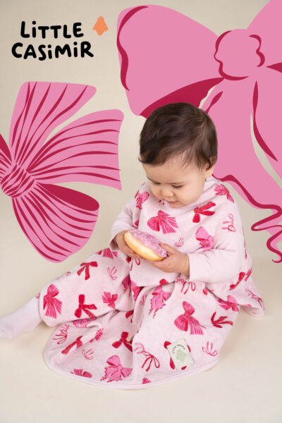 rosafarbener Latz mit Schleifenmotiv an Mädchen, dass Donut isst