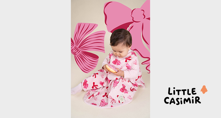 rosafarbener Latz mit Schleifenmotiv an Mädchen, dass Donut isst