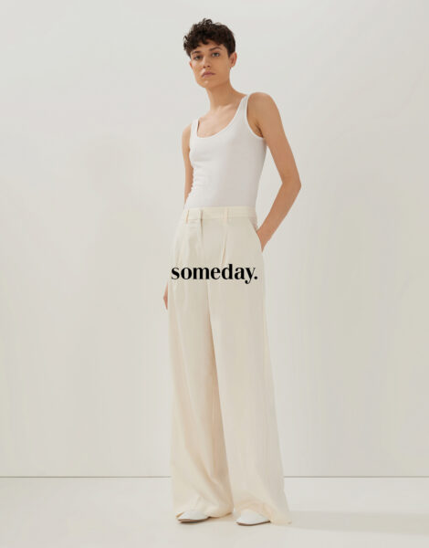 Stehende Frau mit weißem Top und weißer Hose von Someday