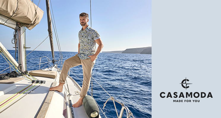 Mann auf Boot stehend in blau gemustertem Hemd und beiger Hose von Casa Moda