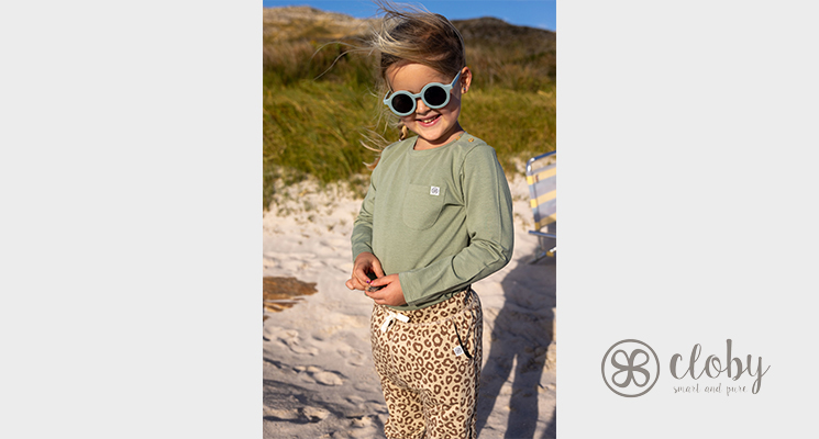Mädchen auf Felsen am Meer in khakifarbenem Langarmshirt und langer Leojeans von Cloby