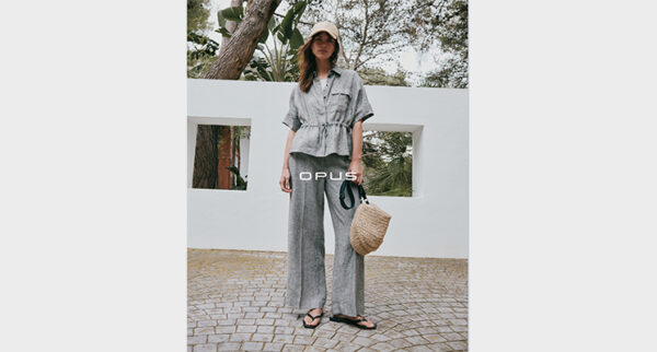 Stehende Frau in hellgrauer Bluse und Hose von Opus