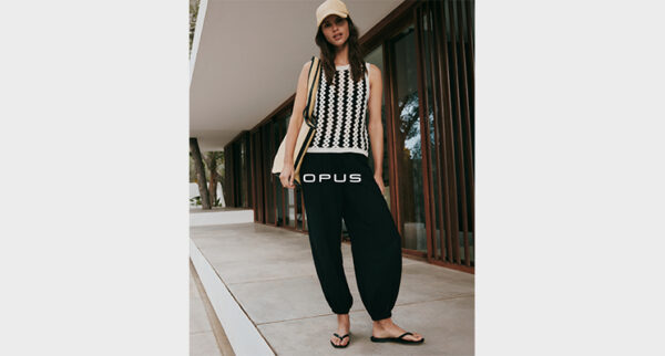 Stehende Frau in weiß schwarzem Top und schwarzer Hose von Opus