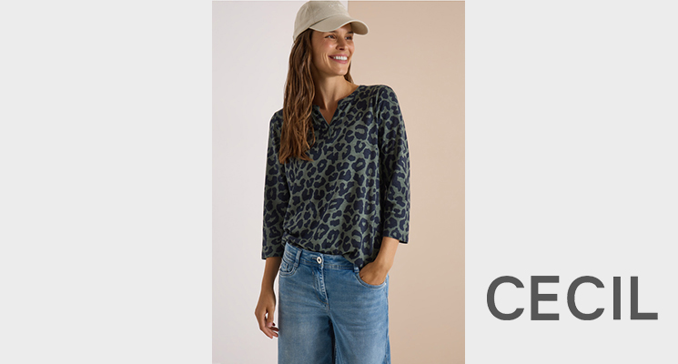 Stehende Frau mit Langarm Shirt in hakischwarzer Tiger Optik blauer Jeans und beiger Cap von Cecil