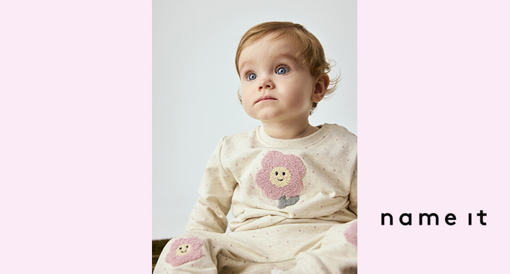 Kleines Mädchen mit cremefarbenem Pullover und Hose mit Blumenprint von Name it