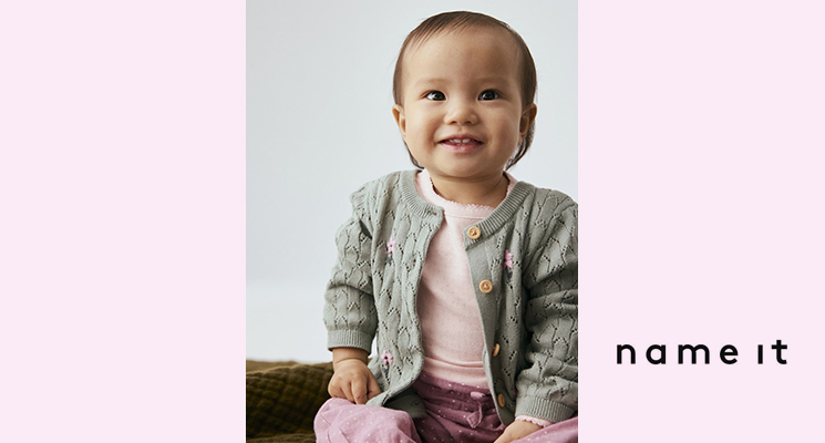 Kleines Mädchen mit rosa Shirt, khakifarbener Strickjacke und rosa Hose von Name it