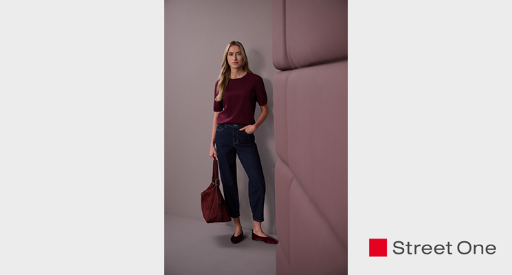 Stehende Frau mit bordeauxfarbenem T-Shirt, baluer Jeans und bordeauxfarbener Tasche von Street One