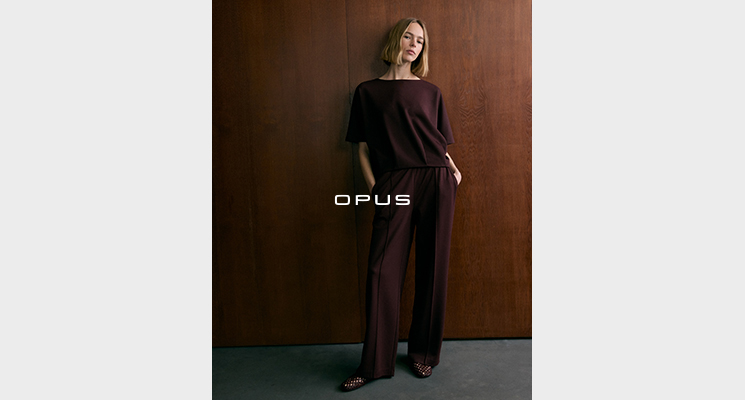 Stehende Frau in bordeuauxfarbenem Langarmshirt und passender langer Stoffhose von Opus