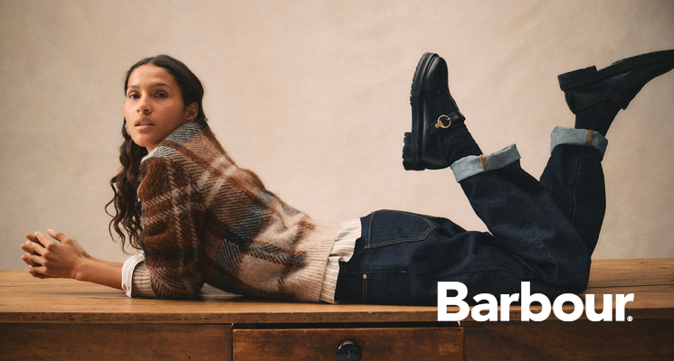 Liegende Dame im karierten Wollpullover und dunkelblauer Jeans von Barbour