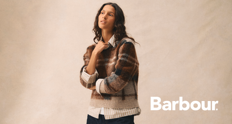 Frau mit kariertem Wollpullover in beige dunkelbraun von Barbour