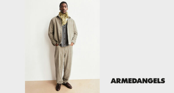 Mann in beiger Jacke, senffarbenem Schal, grauer Weste und beiger Hose von Armedangels