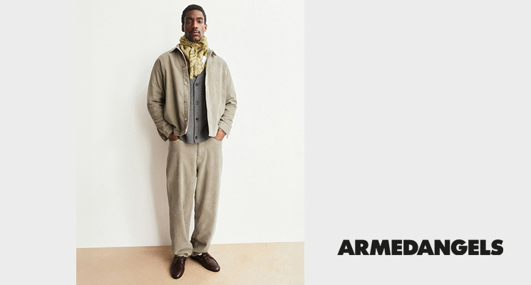 Mann in beiger Jacke, senffarbenem Schal, grauer Weste und beiger Hose von Armedangels