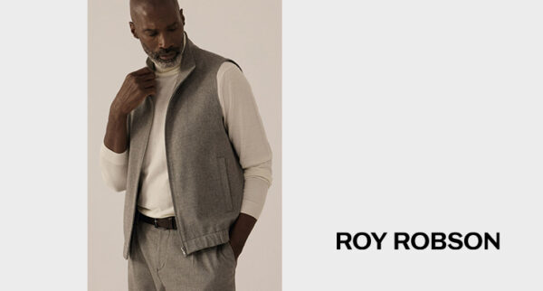 Mann mit grauer Weste und weißem Langarmshirt sowie grauer Stoffhose von Roy Robsen