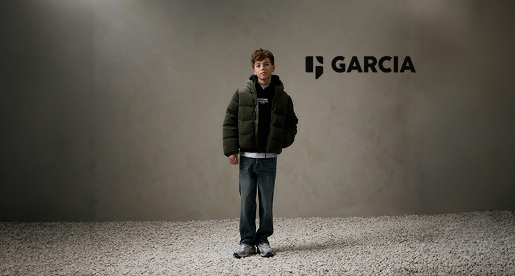 Junge in dunkler Winterjacke mit blauem Kapuzenpullover und grauer Jeans von Garcia