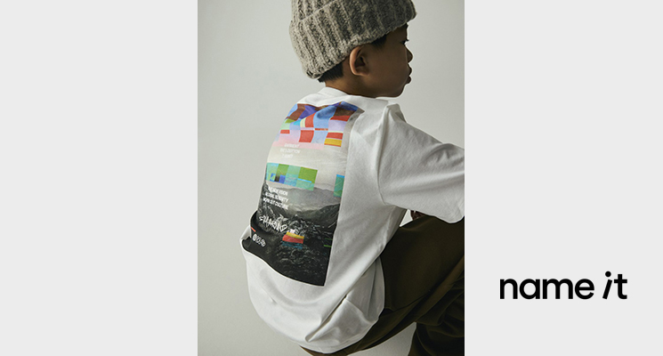 Sitzender Junge in weißem Shirt mit Backprint und dunkler Hose von Name it