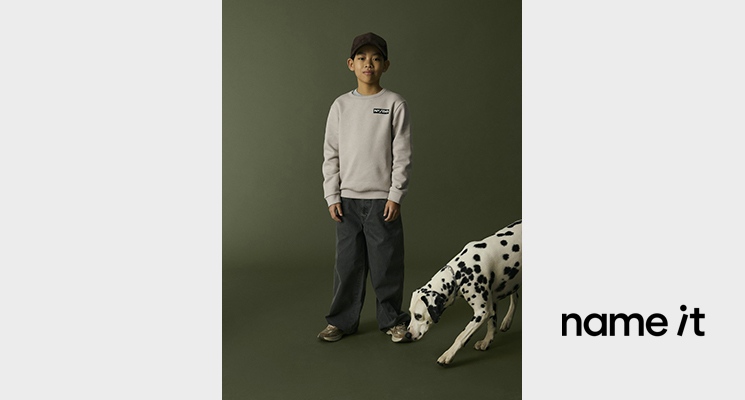 Junge in steinfarbenem Pullover und dunkler Hose von Name it