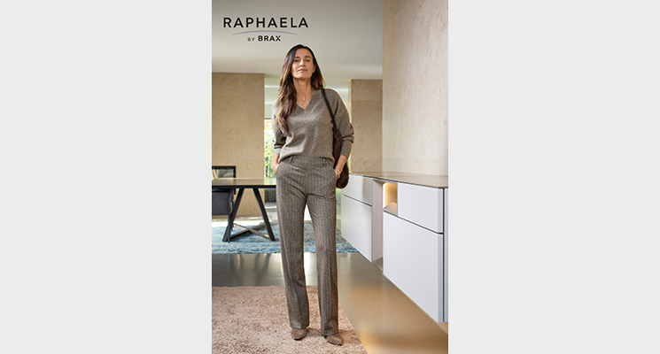 Stehende Frau mit hellbraunem V Ausschnitt Pullover und hellbrauner Streifenhose von Raphaela by BRAX