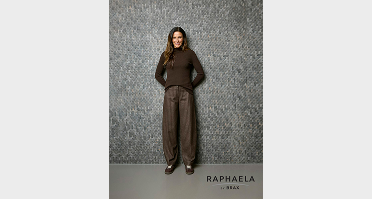 Stehende Frau mit dunkelbraunem Rollkragenpullover und brauner Hose mit Streifen von Raphaela by BRAX