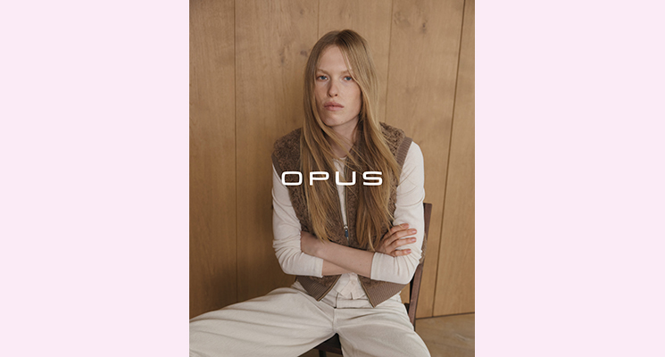 Sitzende Frau mit brauner Fellweste und weißem Langarmshirt sowie brauner Hose von Opus