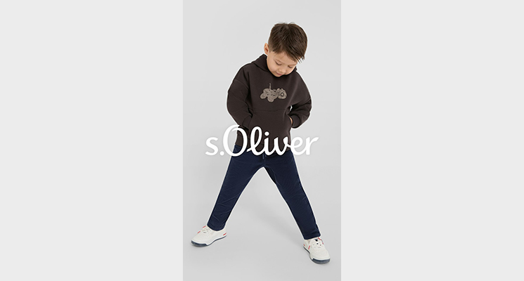 Junge mit braunem Pullover und Aufdruck und schwarzer Hose von S Oliver