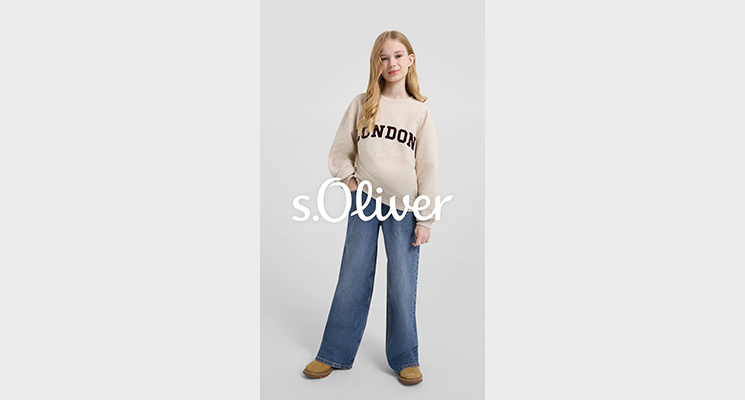 Mädchen mit beigem Pullover mit Schriftaufdruck und blauer Jeans von S Oliver