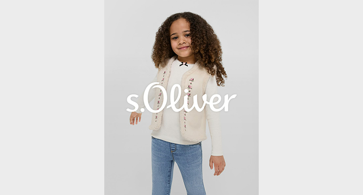 Mädchen in naturfarbener Weste mit Mustern und weißem Langarmshirt und blauer Jeans von S Oliver